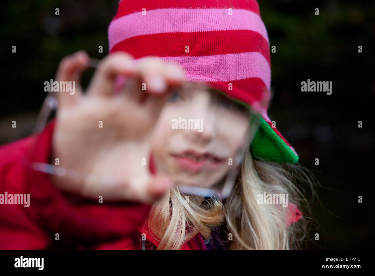 Ragazza cerca attraverso una pace di ghiaccio distorcere il suo volto Foto Stock