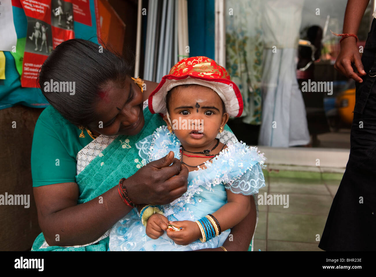 India Kerala, Munnar, madre con giovani femmine bambino vestito in frilly vestito blu e sun Red Hat Foto Stock