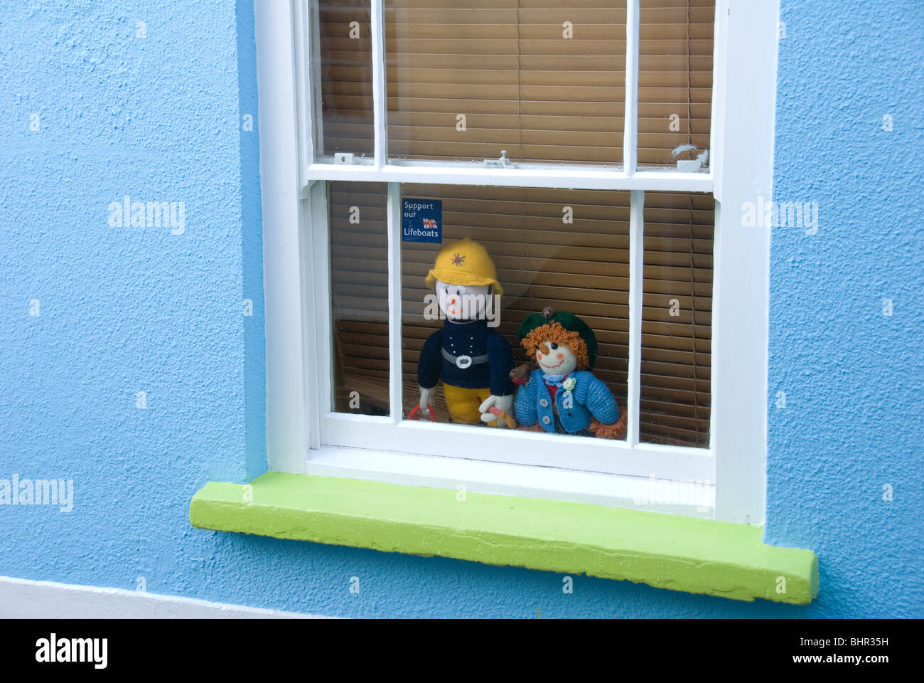 Bambole di maglia vigili del fuoco e lo spaventapasseri in una finestra la raccolta di fondi per le imbarcazioni di salvataggio in Devon UK Foto Stock