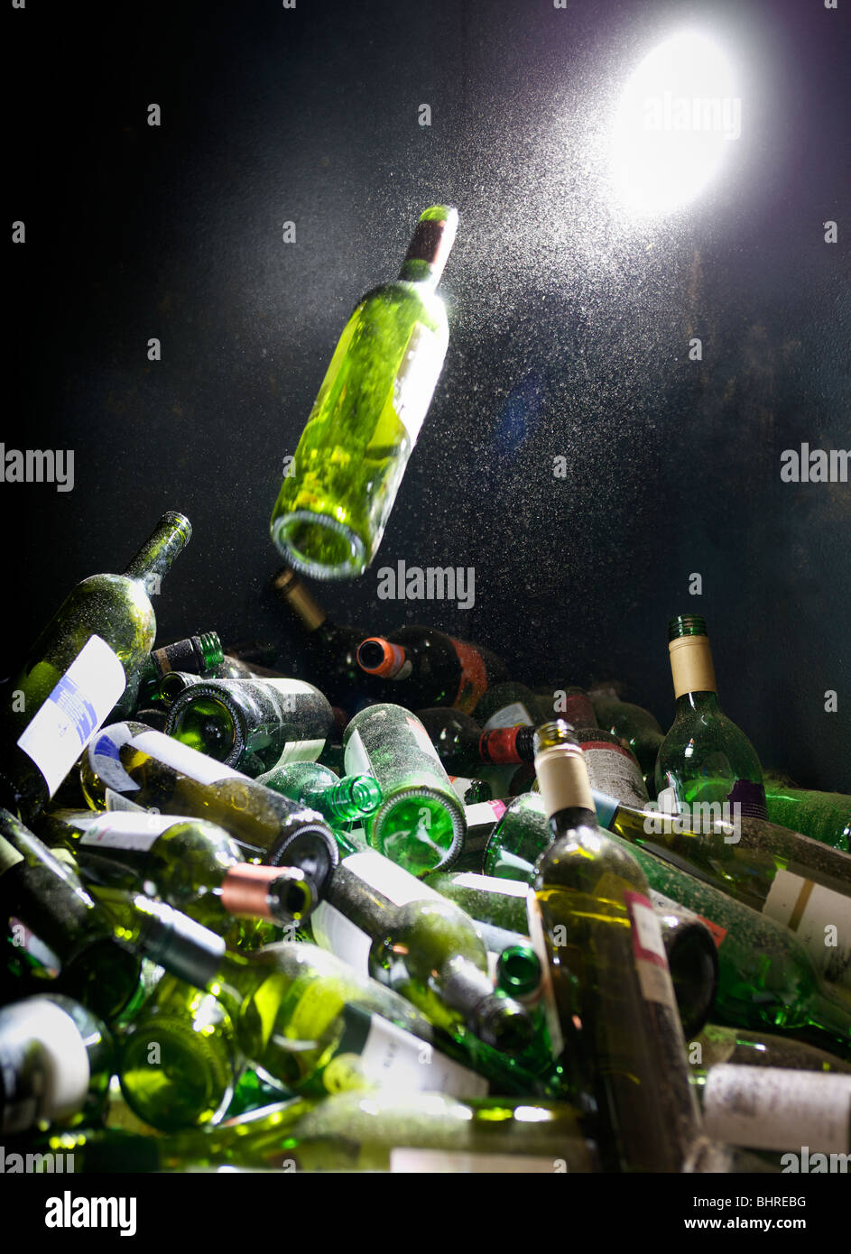 Una bottiglia di vetro che viene spinta in un vetro del contenitore di riciclaggio Foto Stock