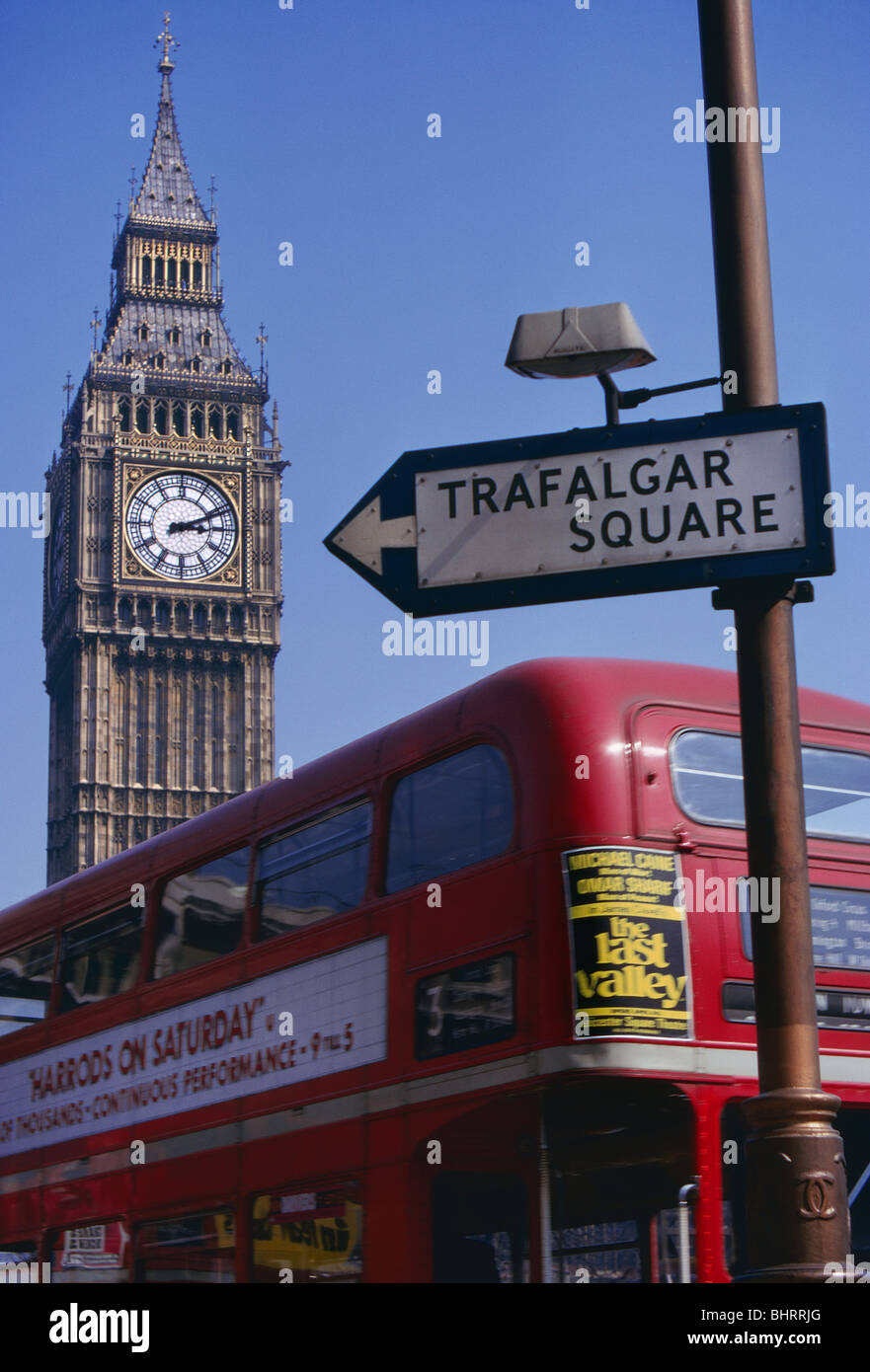 Negli anni settanta il parlamento di Londra bus rosso cartello stradale London Westminster anni settanta archivio storico tradizionale immagine vista del Big Ben presso la sede del Parlamento, con tradizionali red double decker bus routemaster con banner pubblicitari e negli anni settanta il vecchio stile del traffico su strada segno a Trafalgar Square in primo piano. Westminster London REGNO UNITO Foto Stock