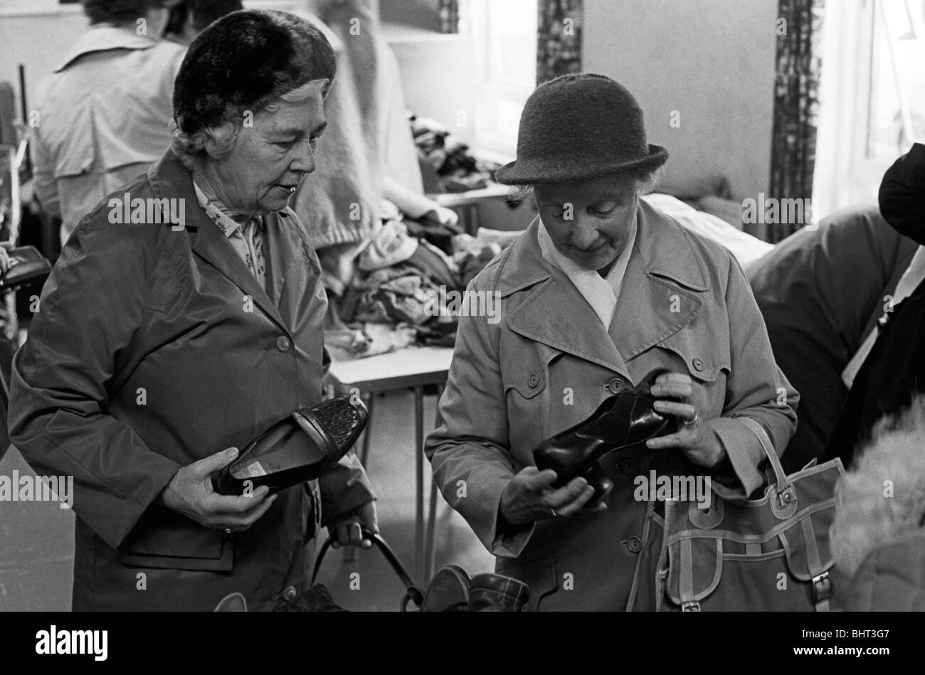 Due signore esaminare scarpe a 1986 accozzaglia vendita nel Galles del Sud città di Abergavenney, Monmouthshire. Foto Stock