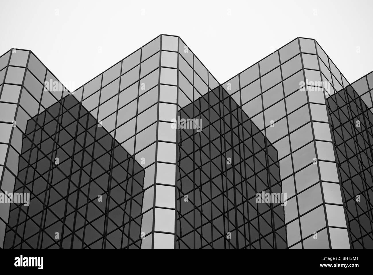 Gli angoli e le riflessioni sulla parte esterna di finestre di vetro su di un moderno grattacielo formando un grafico dei motivi geometrici. Foto Stock