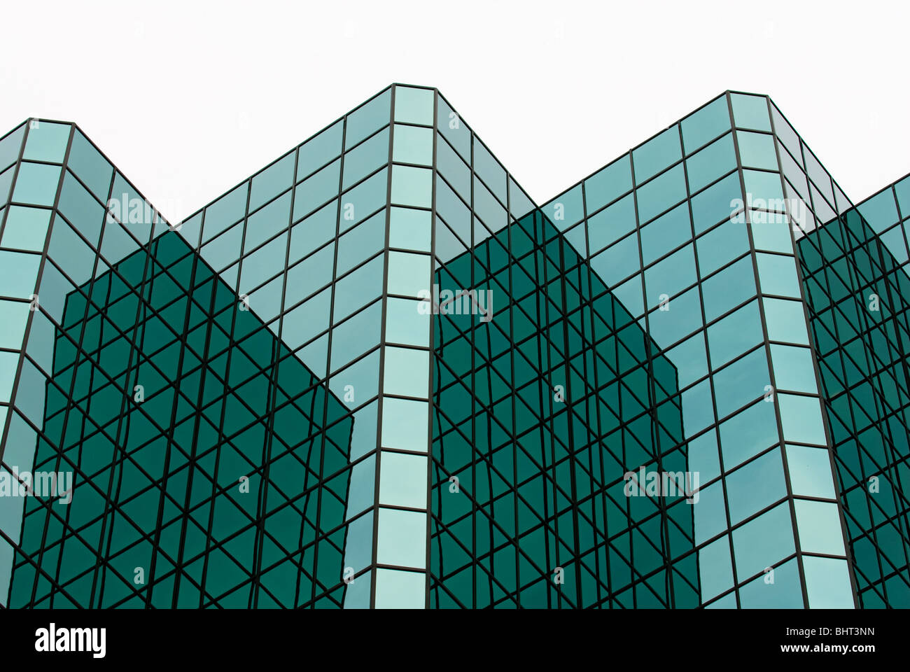 Gli angoli e le riflessioni sulla parte esterna di finestre di vetro su di un moderno grattacielo formando un grafico dei motivi geometrici. Foto Stock
