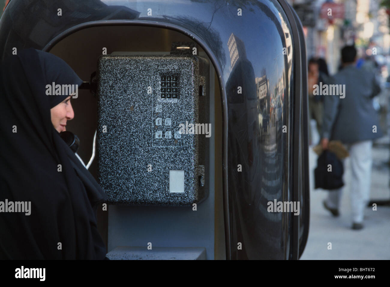 Donna che indossa chador facendo una telefonata in una cabina telefonica, Iran Foto Stock