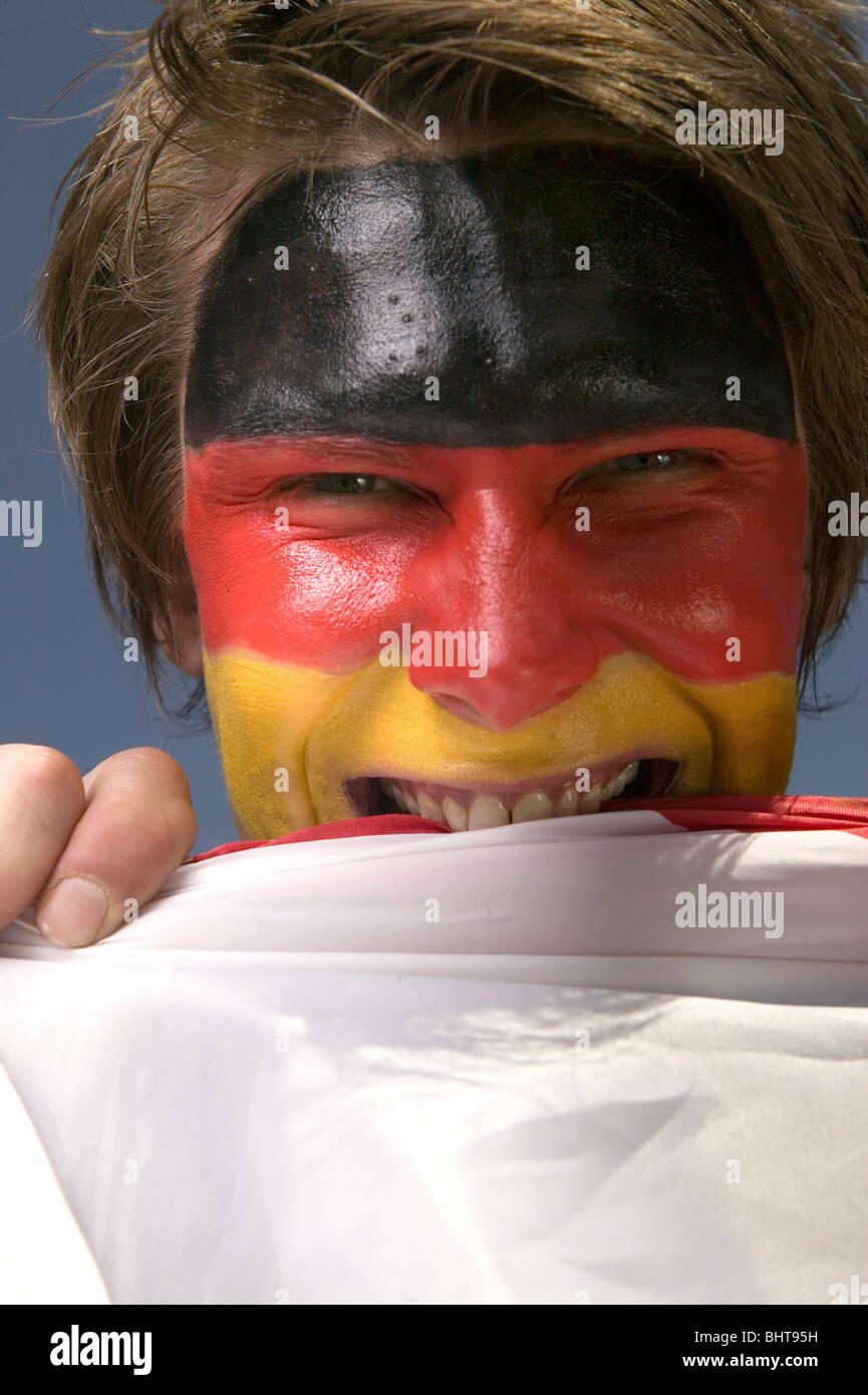 Un arrabbiato tedesco sostenitore di calcio con il tedesco della bandiera dipinta sul suo volto di mordere il St George's bandiera Foto Stock