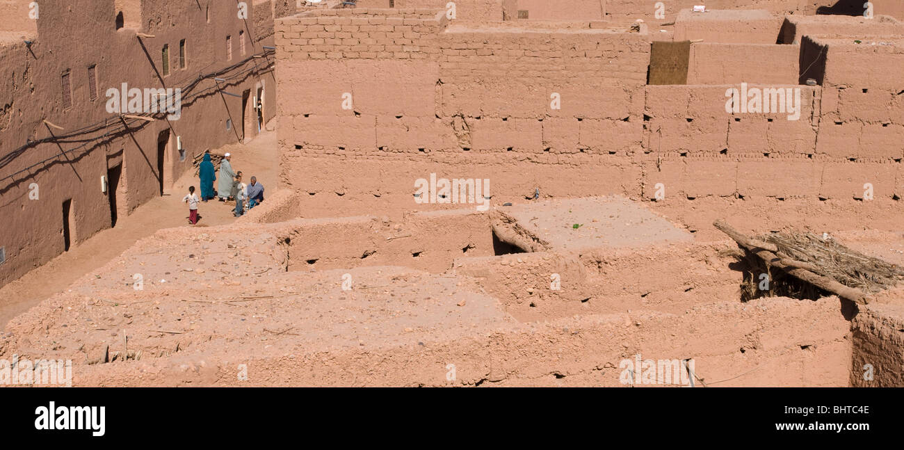 Una famiglia a piedi attraverso il mattone di fango e edifici adobe di Mhamid el Ghizlane nel sud del Marocco Foto Stock