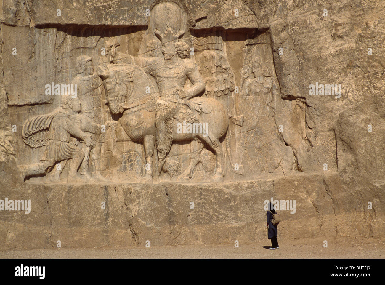 Visitatore presso la grande scultura in pietra a Naqsh-e Rustam scavata una scogliera, nei pressi di Persepolis, Iran Foto Stock