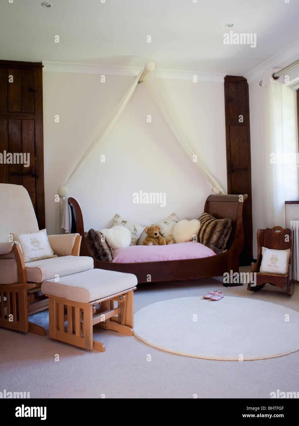Voile bianco oscuranti sopra il letto con i peluche nel bambino camera  moderna con crema poltrona e sgabello e piccolo tappeto circolare Foto  stock - Alamy