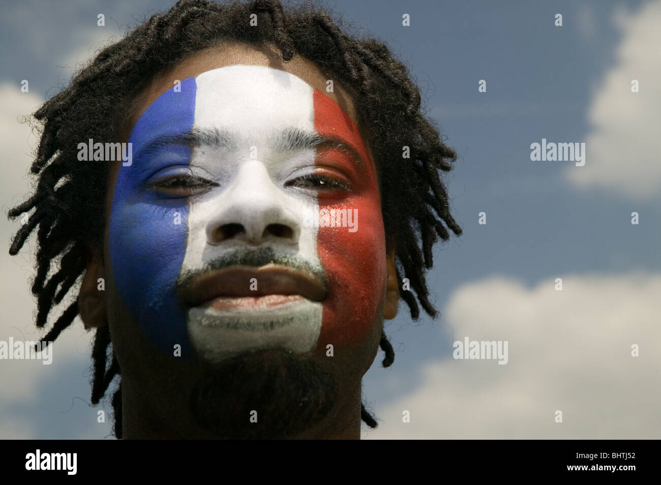 Un Francese patriottico sostenitore di calcio con la bandiera francese dipinto sul suo viso Foto Stock