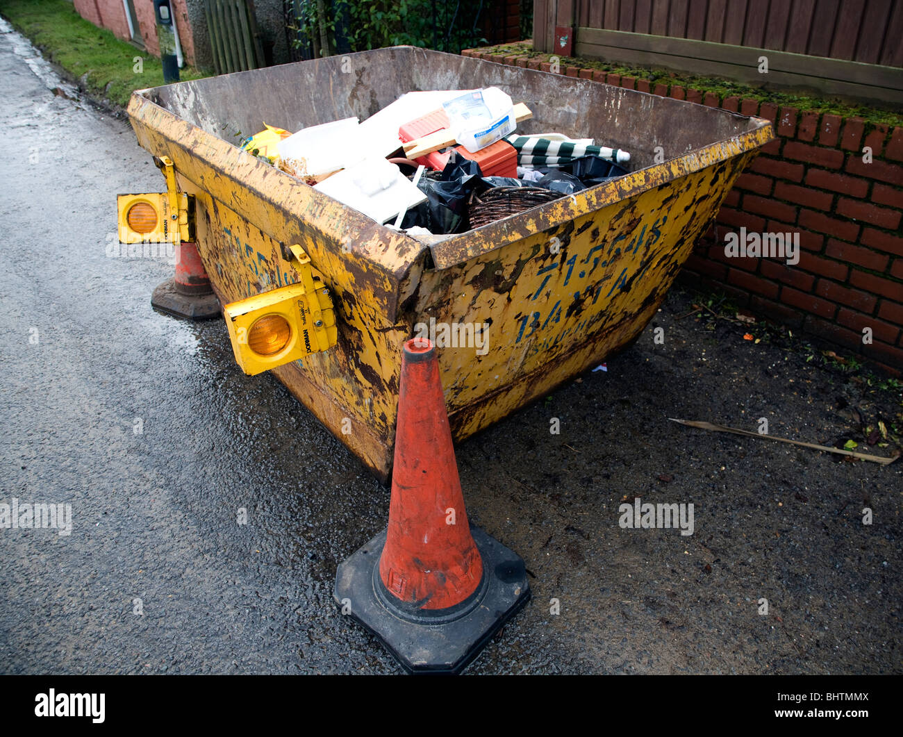 Saltare con i rifiuti domestici in strada arancione cono stradale Foto Stock