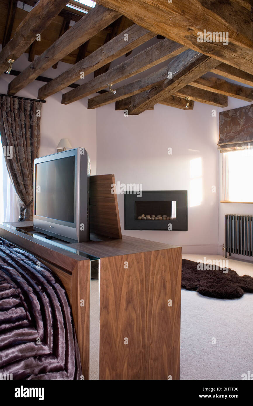 La televisione sul mobile ai piedi del letto in camera da letto moderna con  vecchie travi a soffitto Foto stock - Alamy