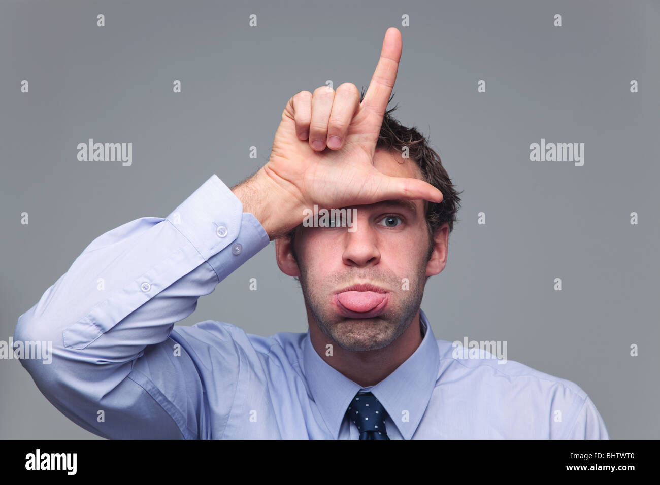 Uomo in camicia e cravatta bloccato la sua lingua fuori e rendendo la lettera L con la sua mano noto come il gesto a mano per il perdente Foto Stock