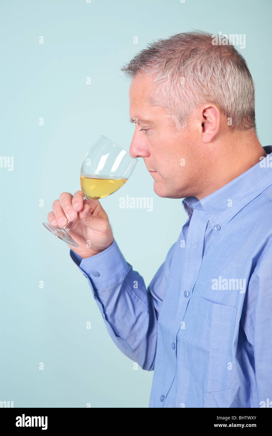 L'Uomo odore di un bicchiere di vino bianco per verificare il profumo Foto Stock