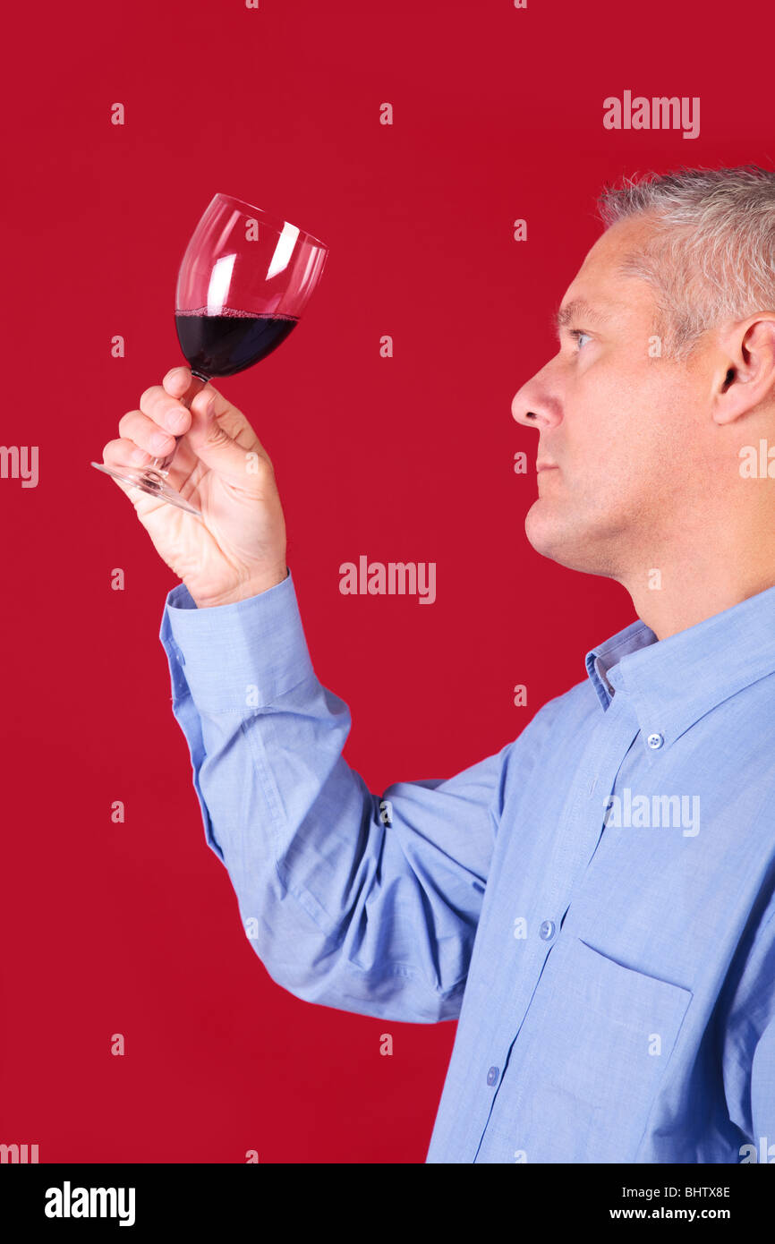 L'uomo la verifica di un bicchiere di vino rosso per chiarezza e qualità Foto Stock