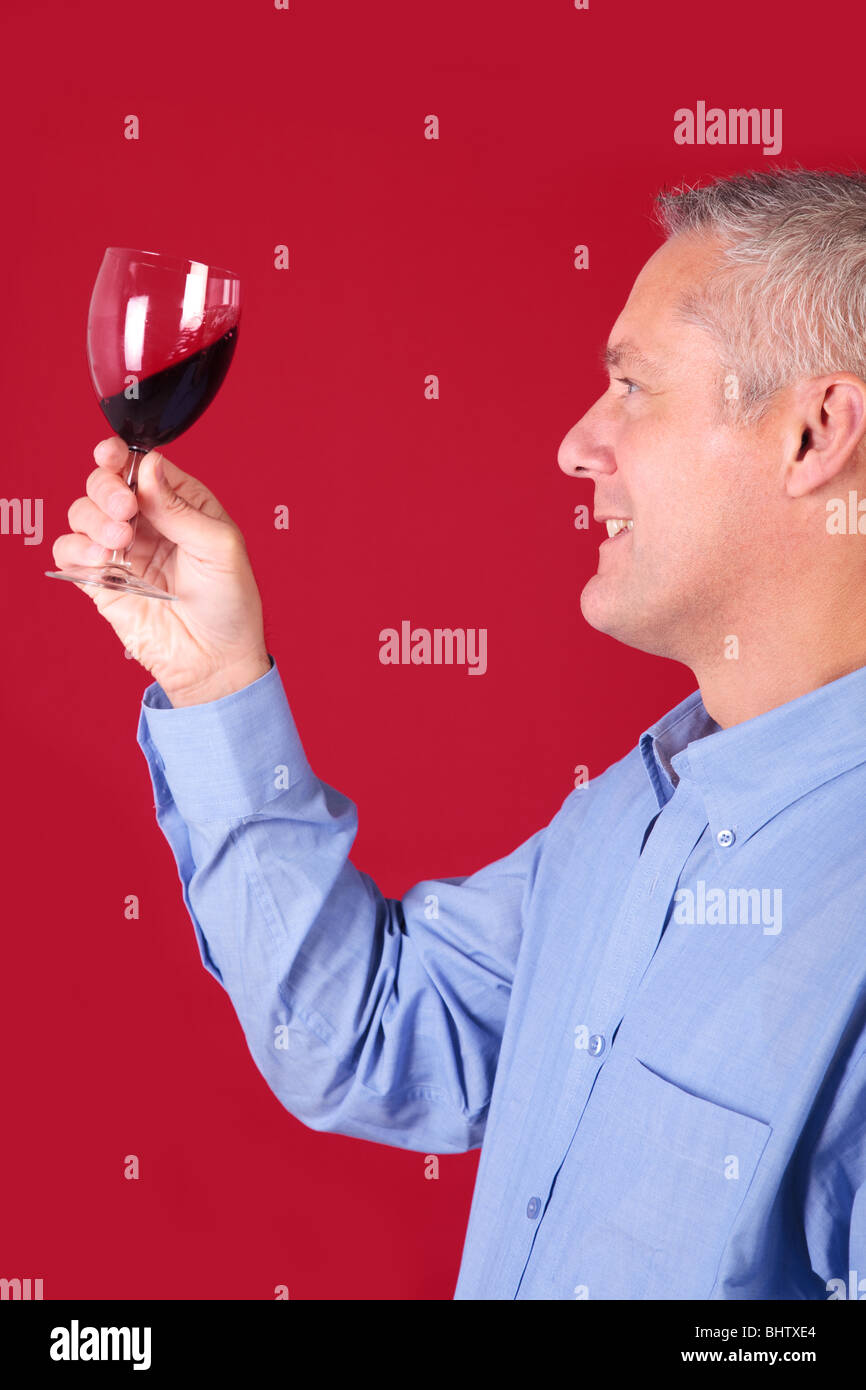 L'uomo la verifica di un bicchiere di vino rosso per chiarezza e qualità Foto Stock