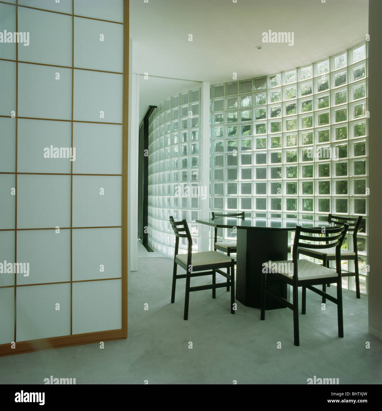Il nero di tavolo e sedie in bianco architettonico sala da pranzo con vetro curvo muro di mattoni Foto Stock