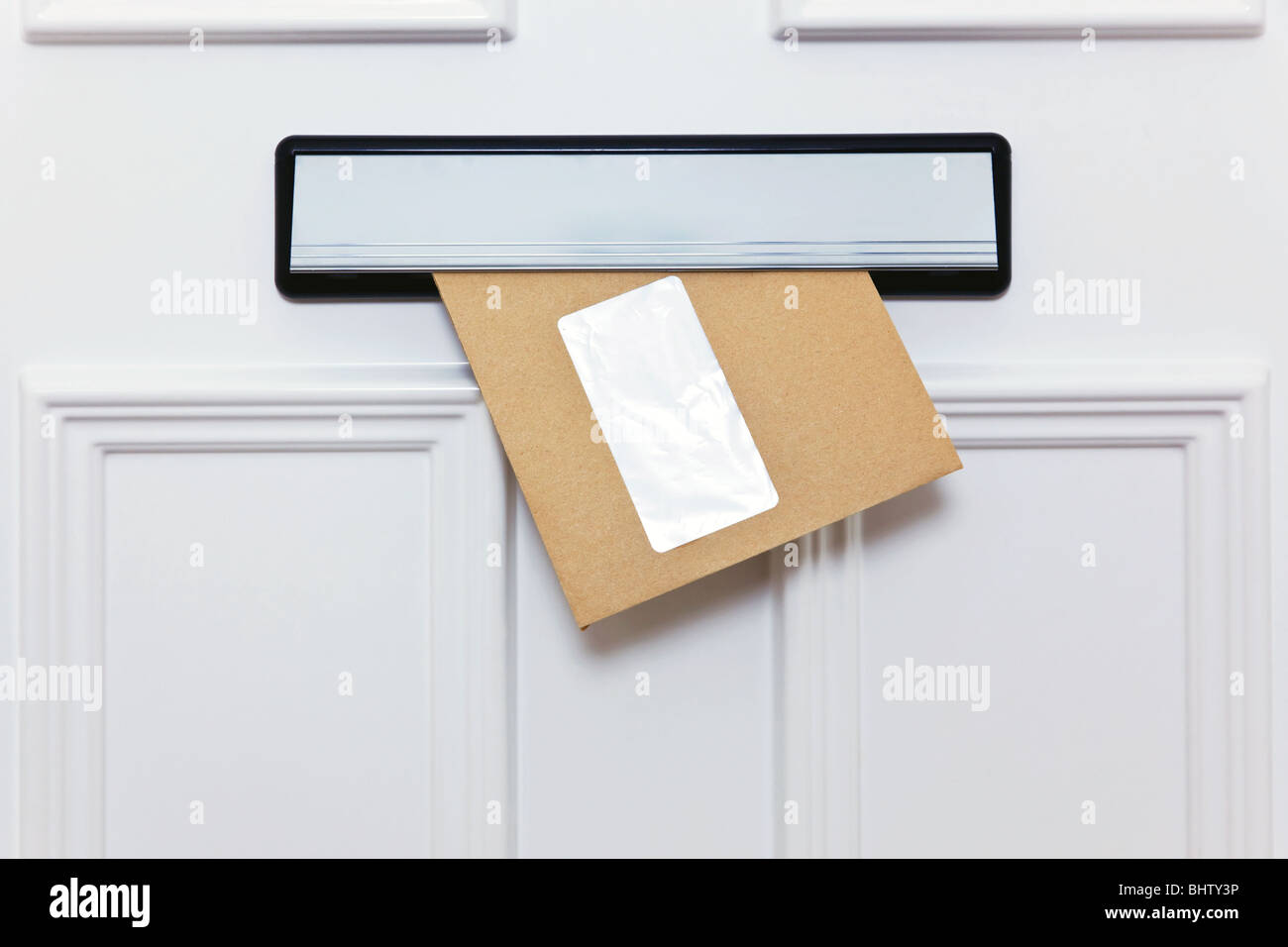 Busta marrone in una porta anteriore letterbox finestra vuota per aggiungere il proprio nome e indirizzo. Foto Stock