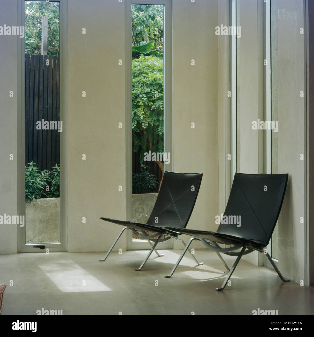 Pelle nera e sedie cromate nella parte anteriore delle alte finestre strette in soggiorno moderno Foto Stock