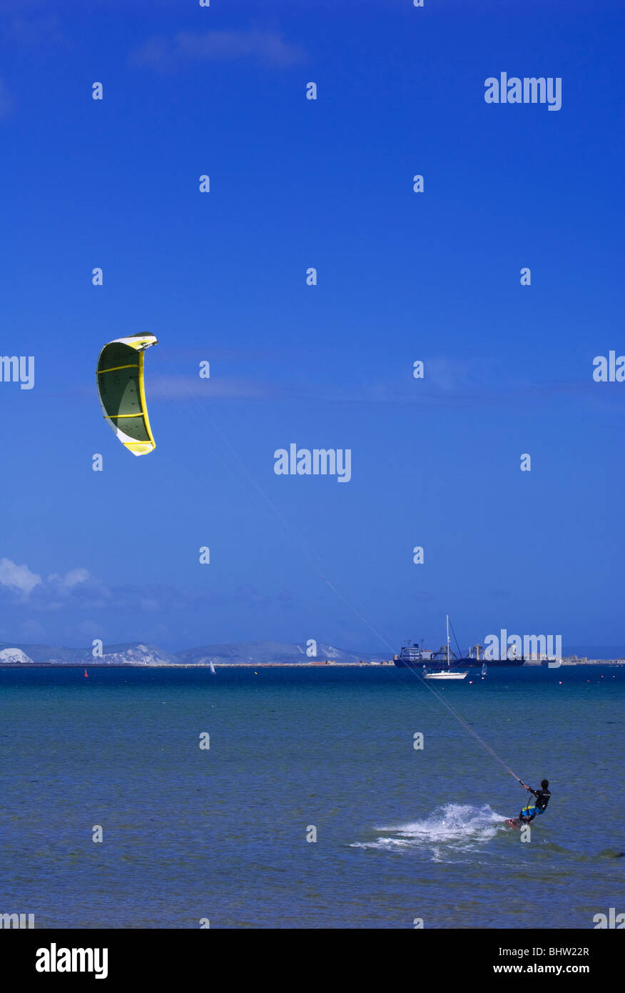 Un kitesurfer viaggia sulla superficie del mare a Portland Harbour, Dorset, Inghilterra, in una giornata calda e soleggiata. Il porto ospiterà alcuni degli eventi di vela alle Olimpiadi del 2012. Foto Stock