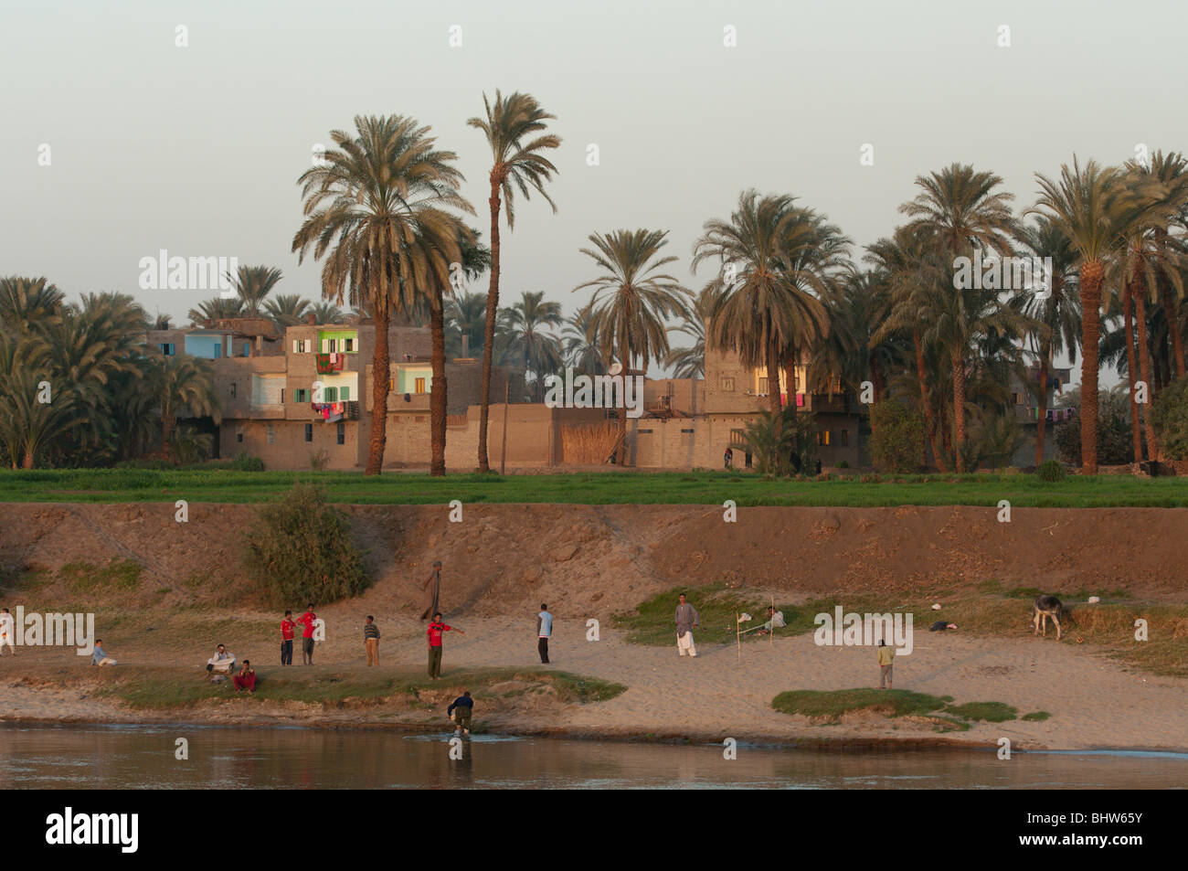 Bambini che giocano sulla riva del fiume Nilo, nei pressi di Luxor in Egitto con la popolazione locale in abiti colorati Foto Stock