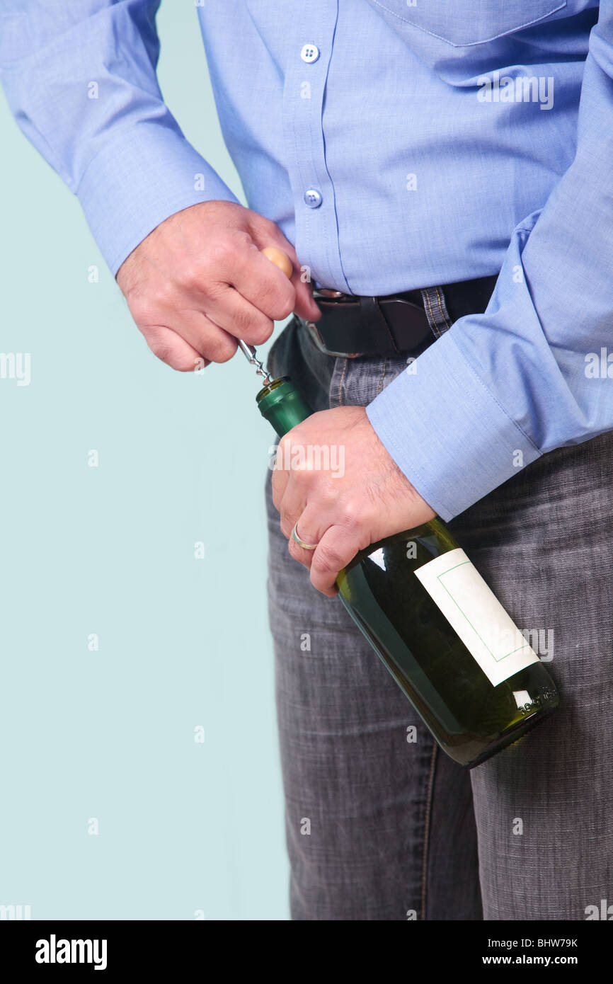 Uomo di aprire una bottiglia di vino bianco con un cavatappi, etichetta vuota per il proprio testo. Foto Stock
