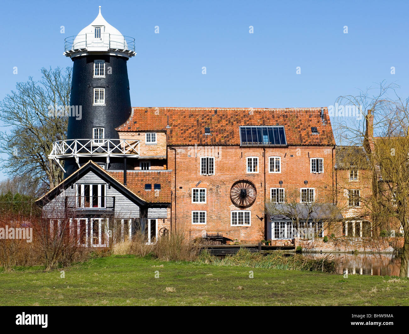 Vecchio bianco e nero windmill dietro grandi convertiti mulino ad acqua Foto Stock