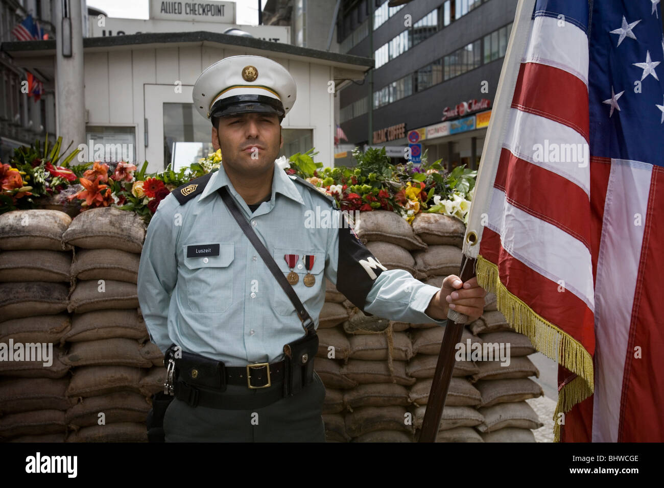 Un soldato americano con una bandiera americana la guardia al Checkpoint Charlie. Berlino Germania Foto Stock