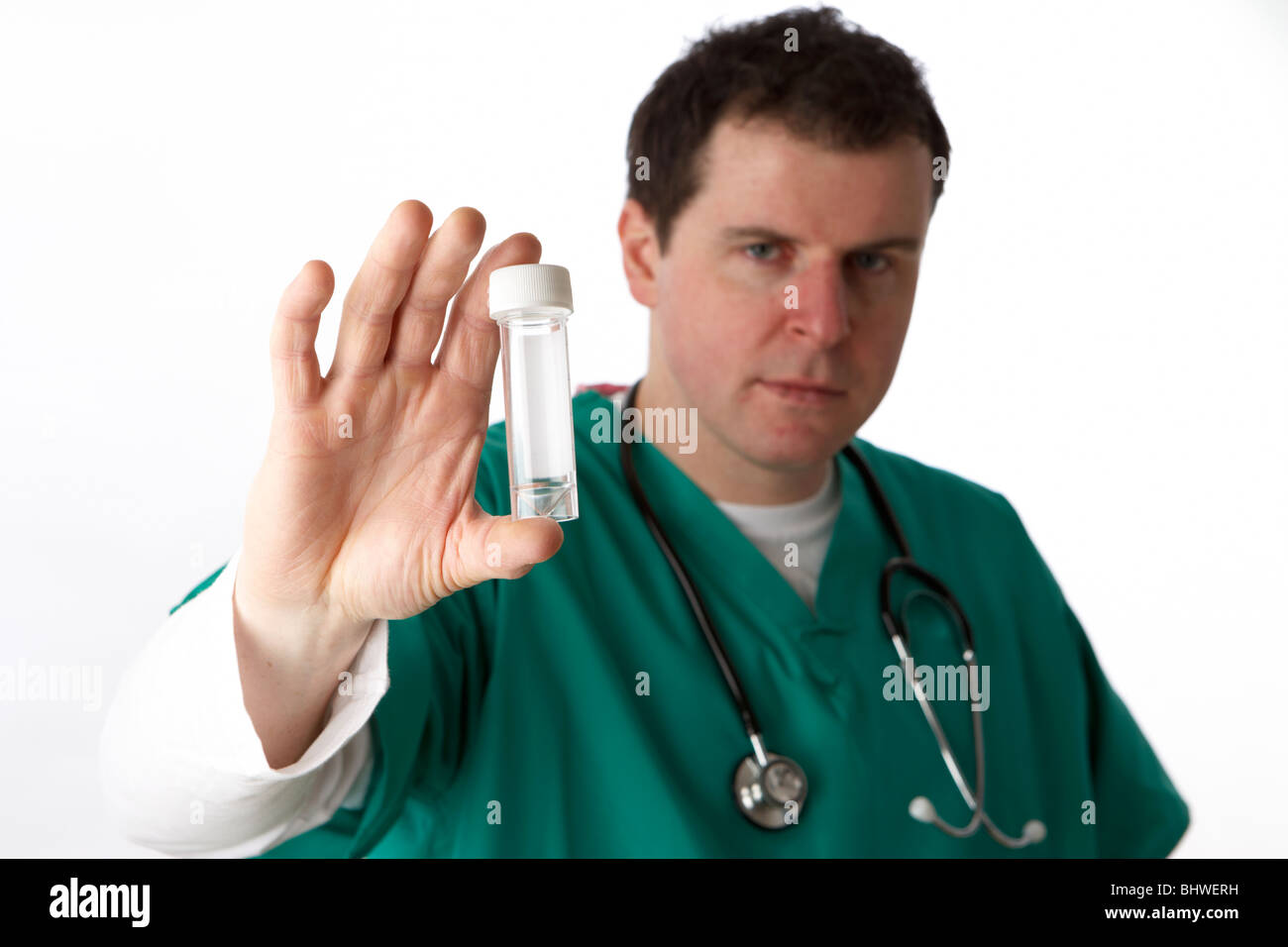 Uomo che indossa medical scrubs tenendo fuori campione bottiglia campione vuota Foto Stock