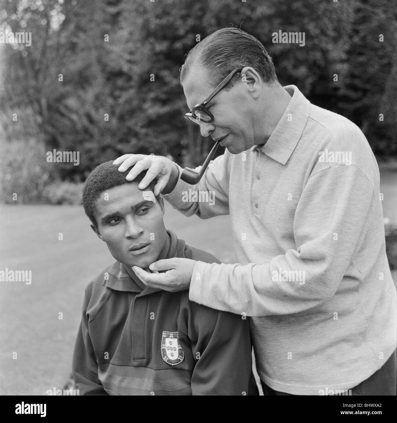 1966 World Cup in Inghilterra. Un aspetto di preoccupazione sulle facce del Portogallo star Eusebio e il team medico Joao Da Silva Rocha sull'occhio che necessitavano di cucitura dopo la partita contro l'Ungheria. Il 15 luglio 1966. Foto Stock