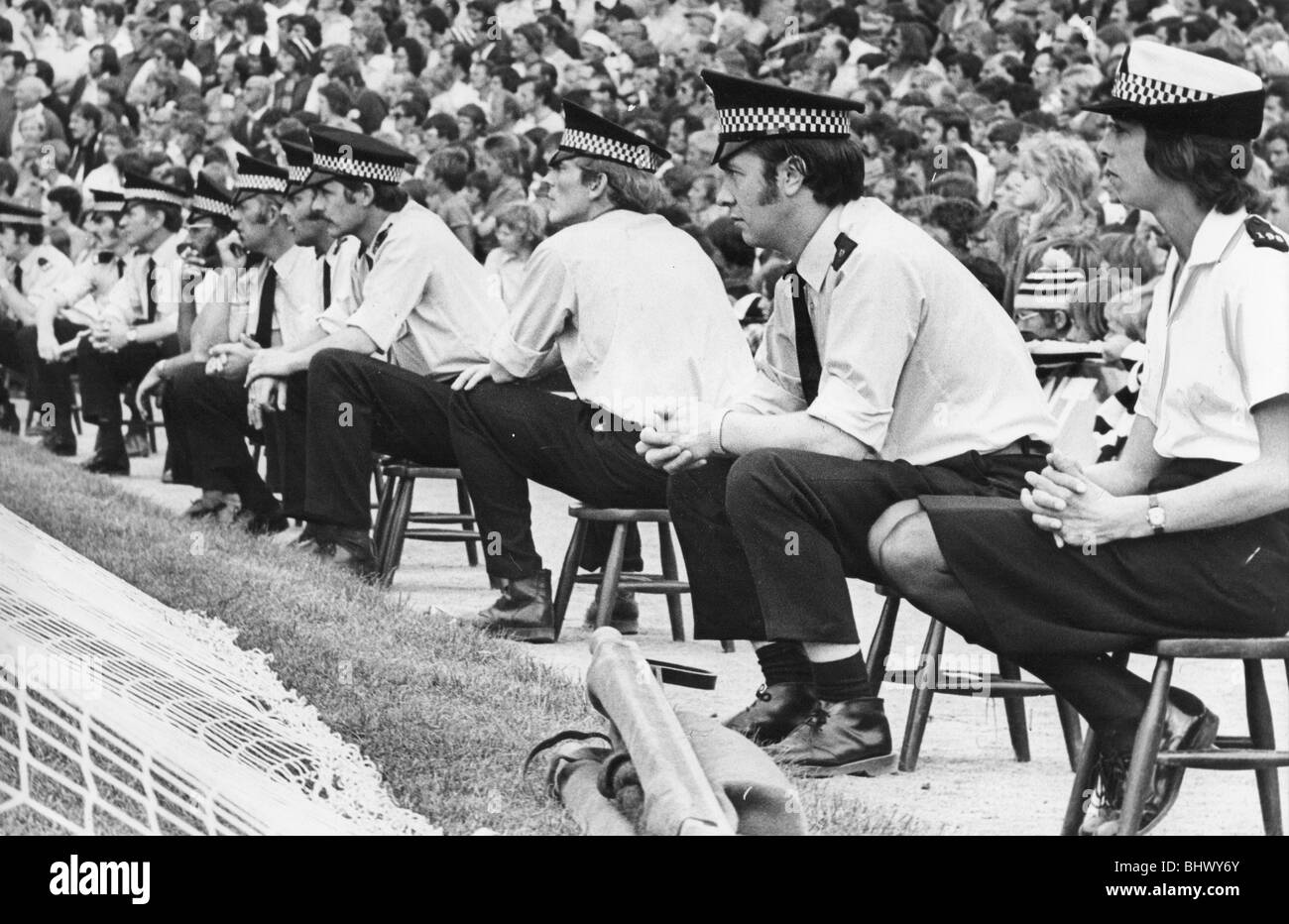 Una linea di poliziotti e di controllo delle donne il Newcastle United fans presso il St James Park 21 agosto 1976 problemi sulle strade di Newcastle quando Sunderland è arrivato in città durante gli anni settanta. Polizia montata ripristinare l'ordine mentre un cane di polizia assume un gustoso boccone di una ventola della gamba dei pantaloni! Controllo gradualmente è stata ritrovata all'interno di stadi. A St James Park un enorme la presenza della polizia è stato necessario per alcuni mentre - e avevano un loro mini-sgabelli per godersi l'azione! Foto Stock