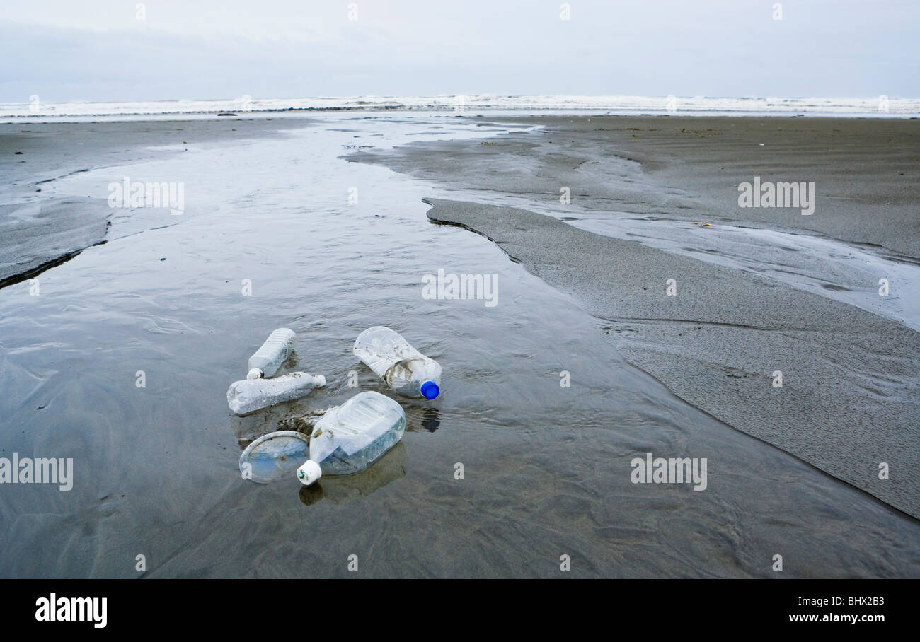 Bottiglie di plastica e coperchi seduto in un ruscello che scorre fuori all'Oceano Pacifico. Foto Stock