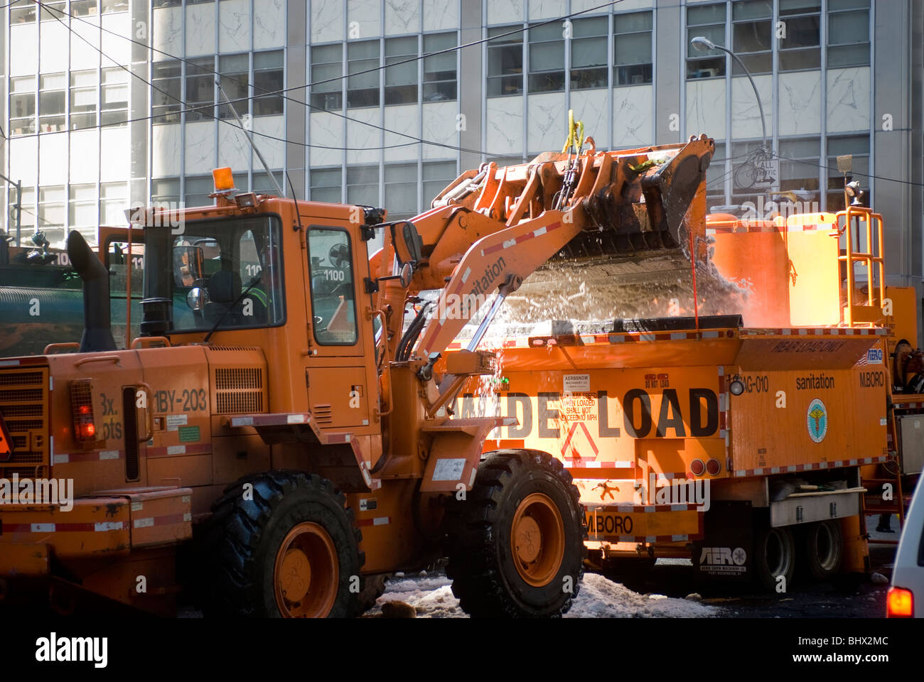 NYC Dipartimento di Igiene lavoratori utilizzano un caricatore frontale per il deposito di neve in un forno di fusione di neve nella parte inferiore di Manhattan a New York Foto Stock