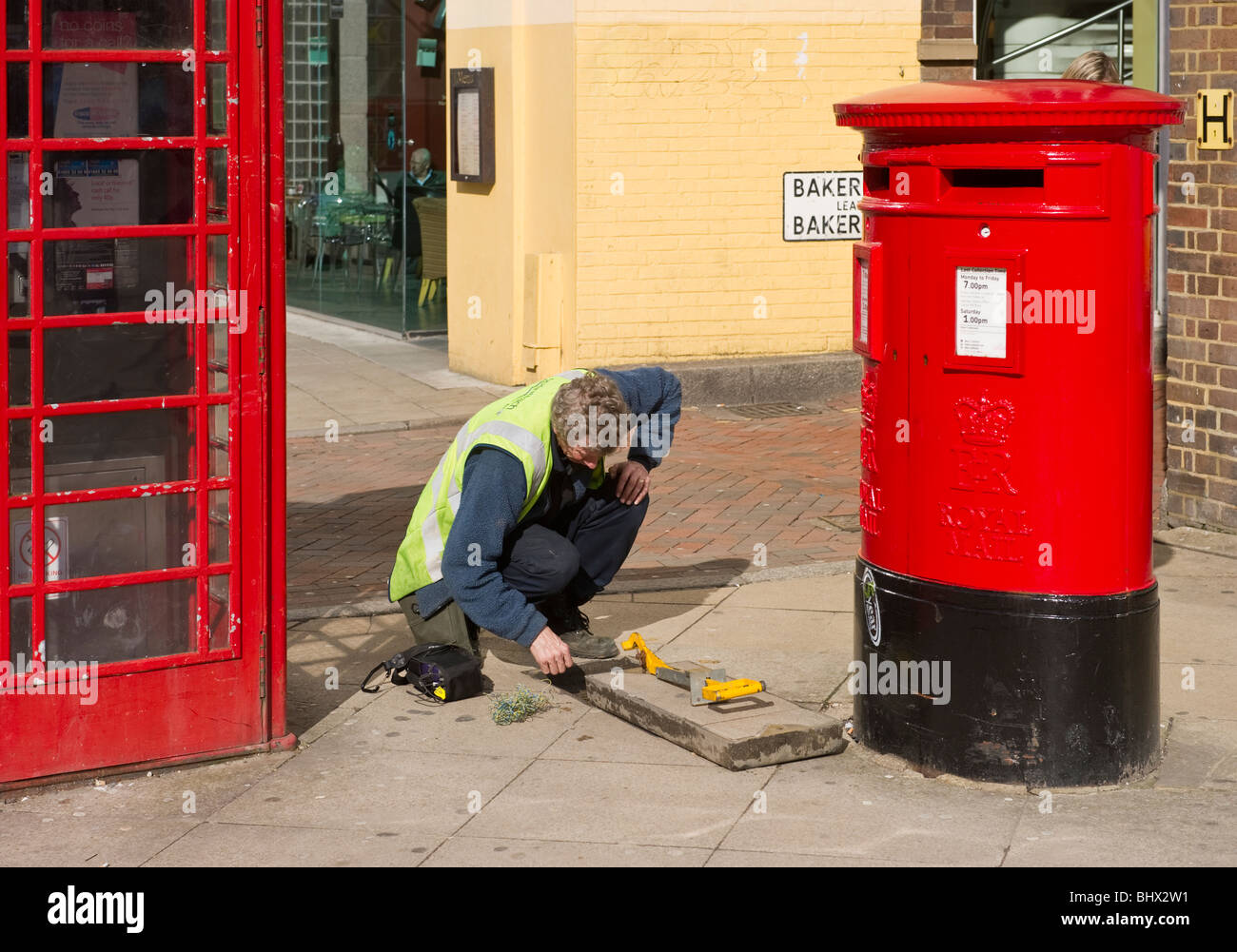 Un ingegnere elettrico riparazione dei cablaggi probabilmente filo telefonico al di sotto di una pavimentazione in Uxbridge West London REGNO UNITO Foto Stock
