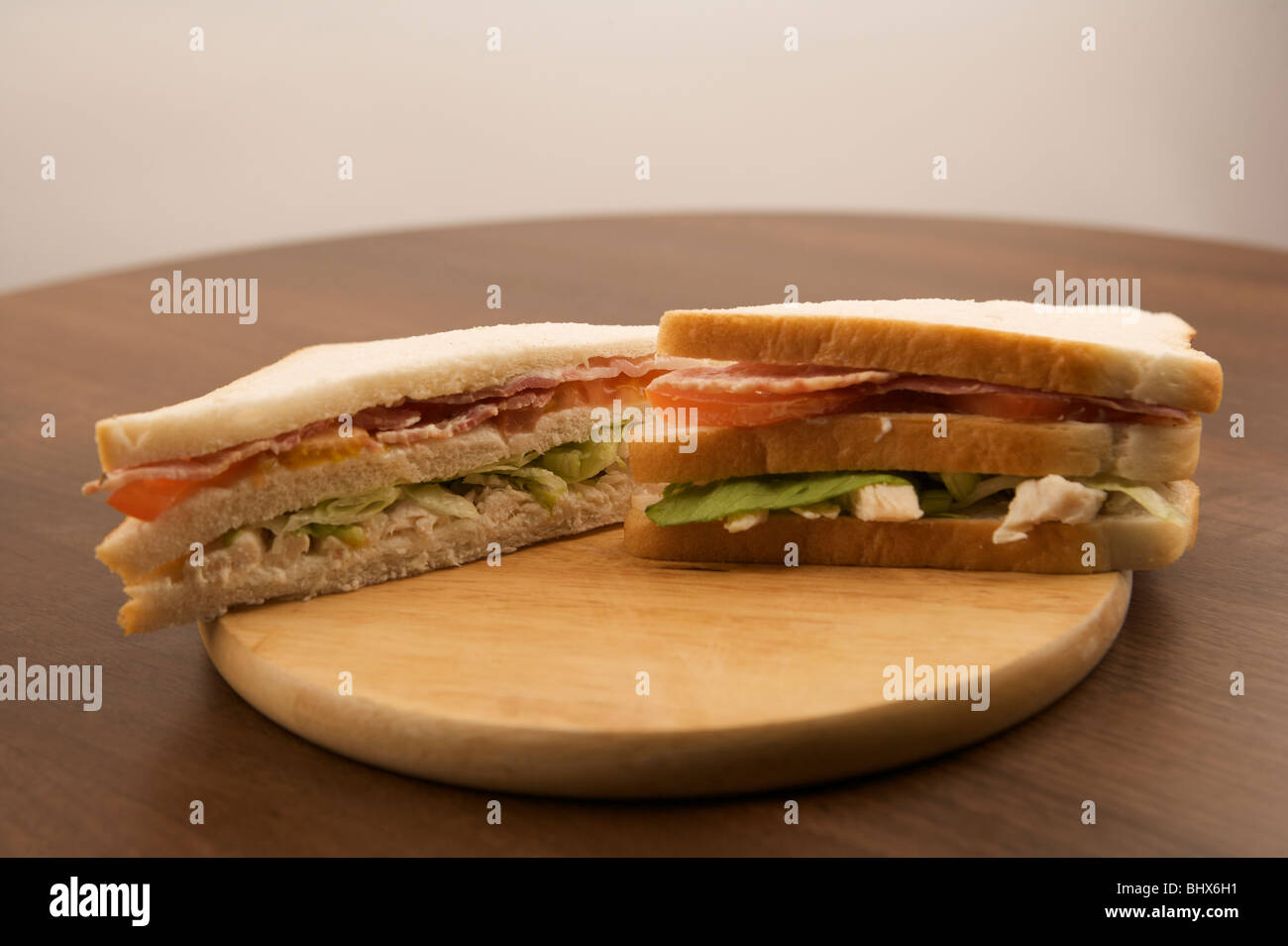 Bacon, lattuga, pomodoro Sandwich di Pollo noto anche come BLT su un pane a bordo o tagliere Foto Stock