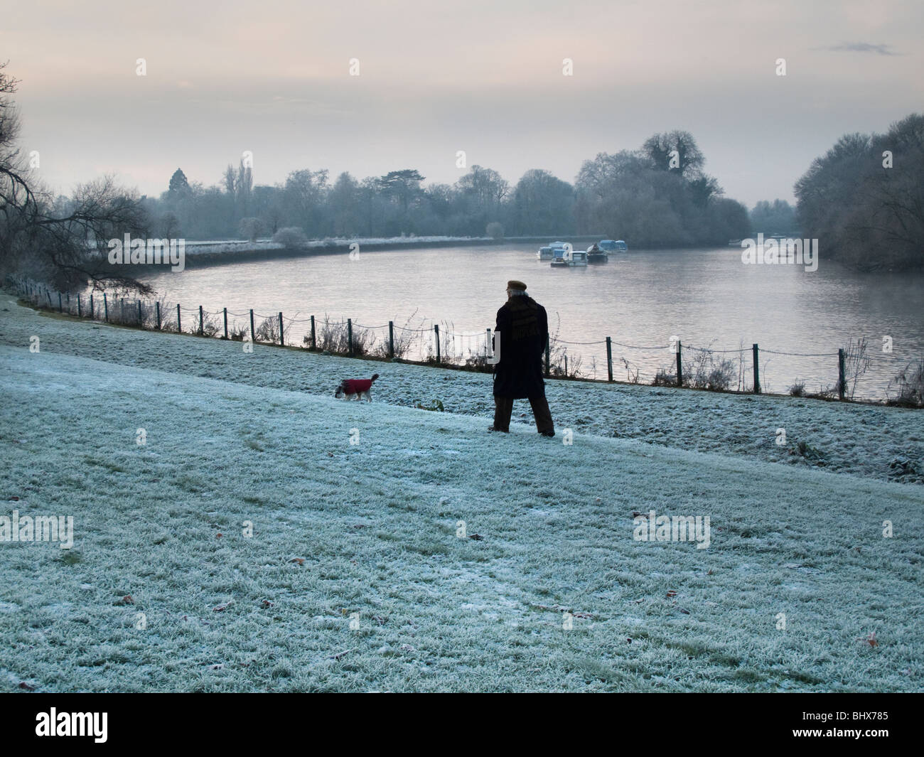 Uomo che cammina il cane su un gelido mattino,Richmond Upon Thames,Surrey, Inghilterra Foto Stock