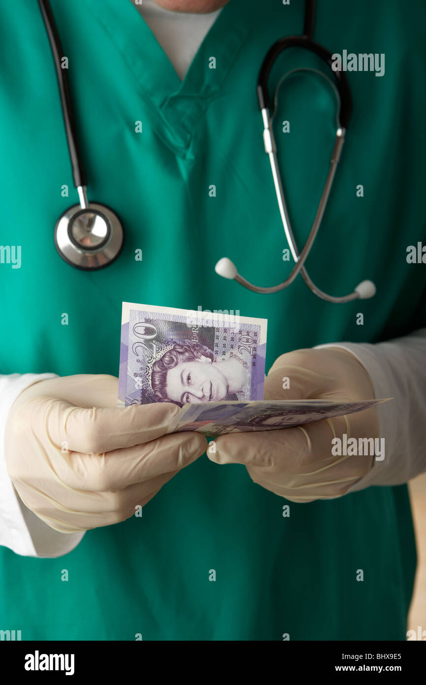 uomo che indossa scrub medici e stetoscopio contando 20 sterline banconote junior medico paga stipendio salari denaro Foto Stock