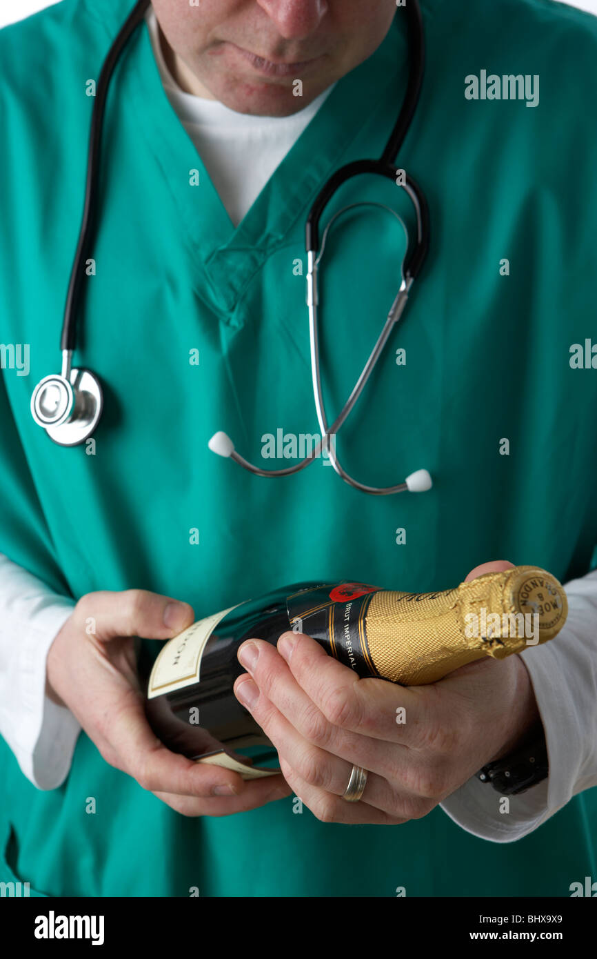 Uomo che indossa medical scrubs e stetoscopio tenendo la bottiglia di champagne Foto Stock