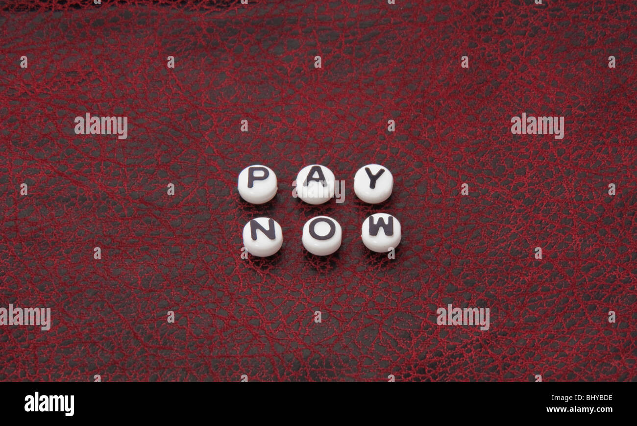 Le parole pagare adesso è parte di questa serie in bianco e nero scritte in tondo i talloni su una pelle nera e rossa superficie testurizzata. Foto Stock