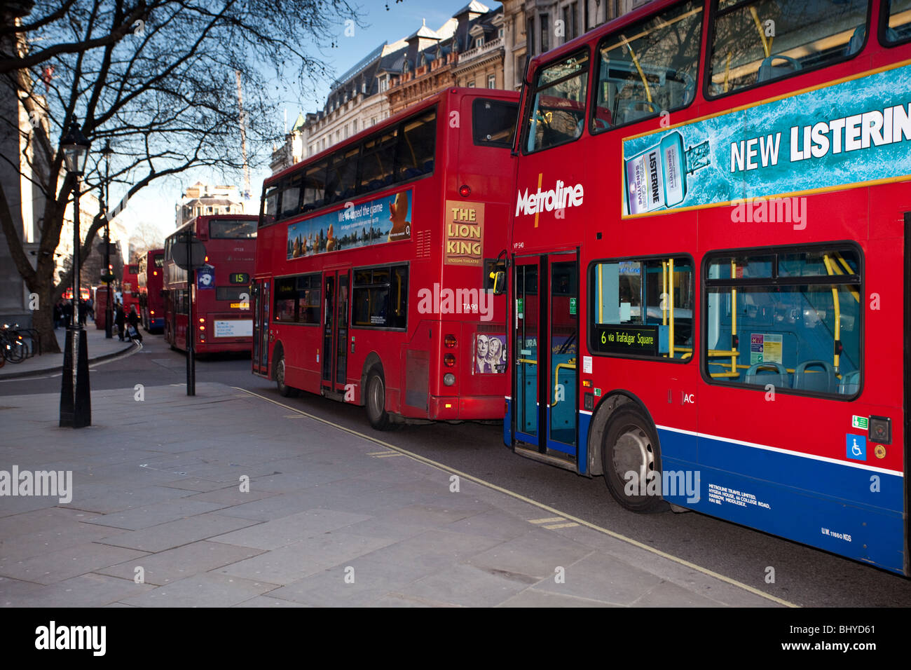 L'immagine mostra una fila di Red London Double Decker bus in coda fino ad attraversare Trafalgar Square a Londra. Foto Stock