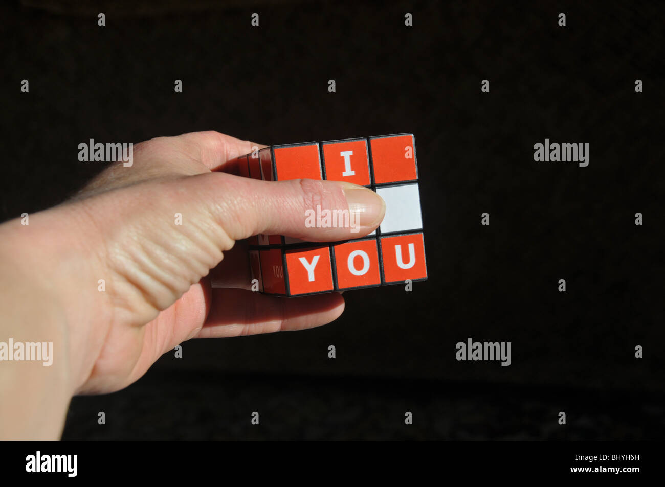 Mano che tiene un "ti amo" puzzle cube con il dito pollice, nascondendo la parola "amore". Foto Stock