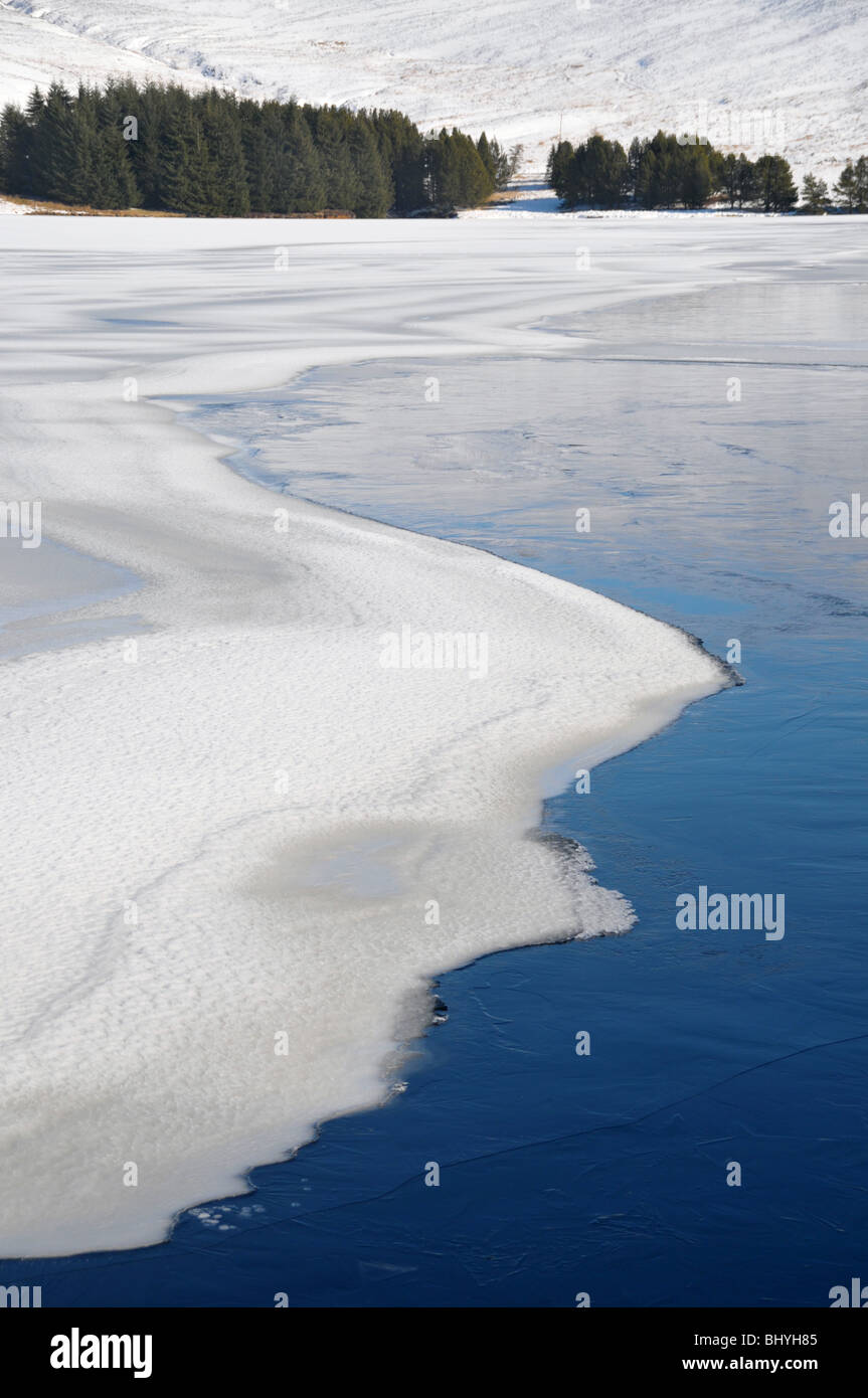 Abstract delle backwaters serbatoio, con ghiaccio congelato e la neve su acqua con abeti su lontano bordo d'acqua. Foto Stock
