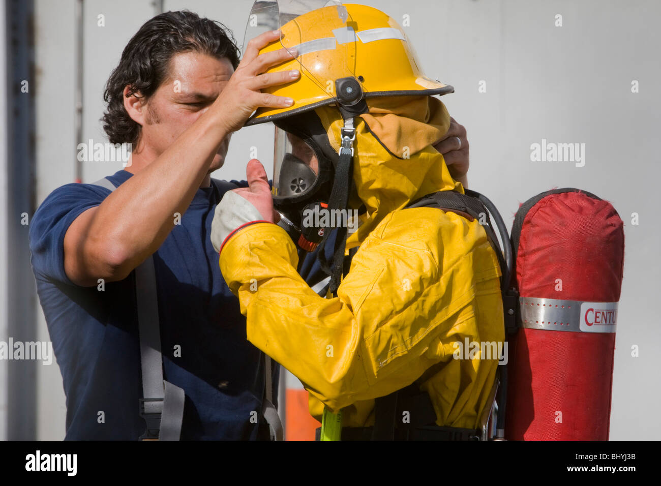 Un vigile del fuoco è assistito per avere il kit messo sulla prima di affrontare un materiali pericolosi incidente Foto Stock
