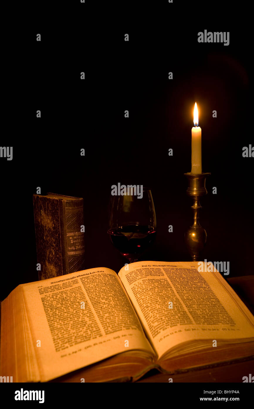 Vecchio libro aperto, un bicchiere di vino rosso e una candela Foto Stock