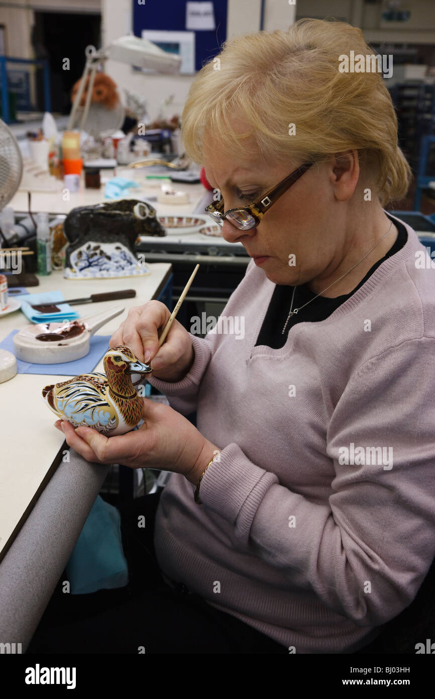 Royal Crown Derby fabbrica, Derby - gilder Julie Towell ultimando un anatra fermacarte. Foto Stock
