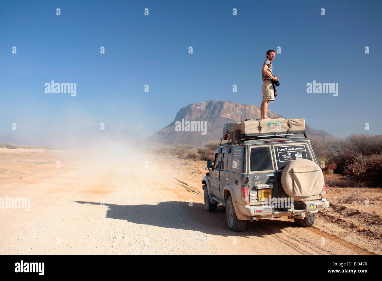 L'uomo sul piano di un veicolo fuoristrada nel nord del Kenya come un altro veicolo va passato Foto Stock