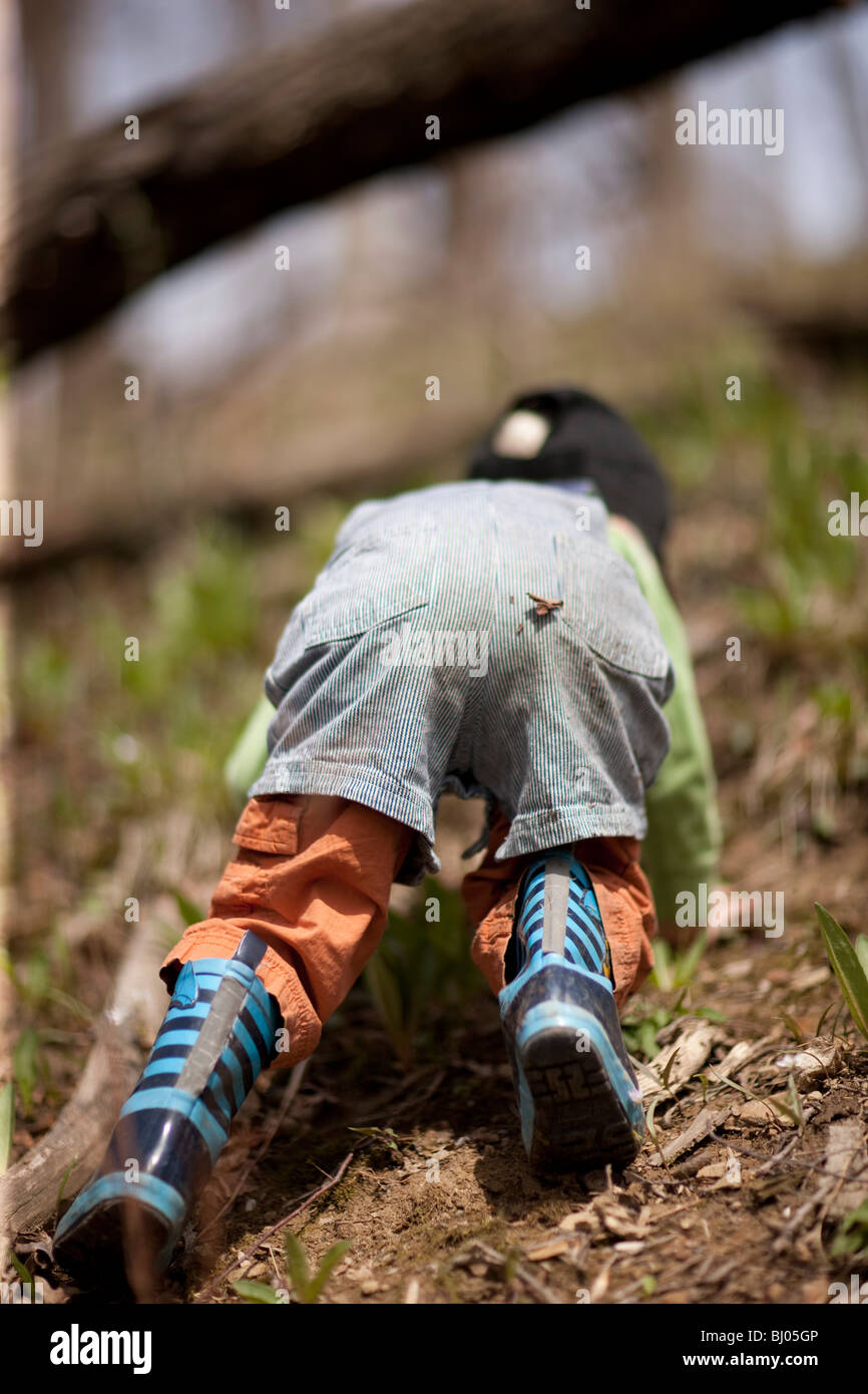 Ragazzo di indossare stivali di gomma salendo fino alla cima di una collina  nel bosco Foto stock - Alamy