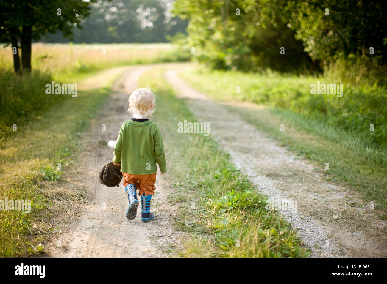 Giovane ragazzo in piedi su una strada di ghiaia. Foto Stock