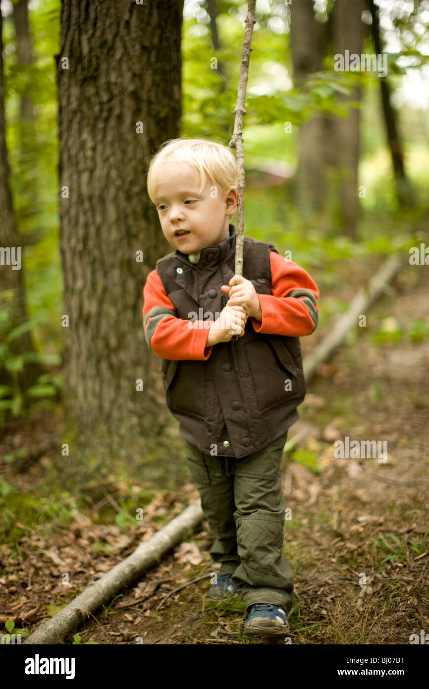 Ragazzo giovane a piedi nei boschi con un bastone. Foto Stock
