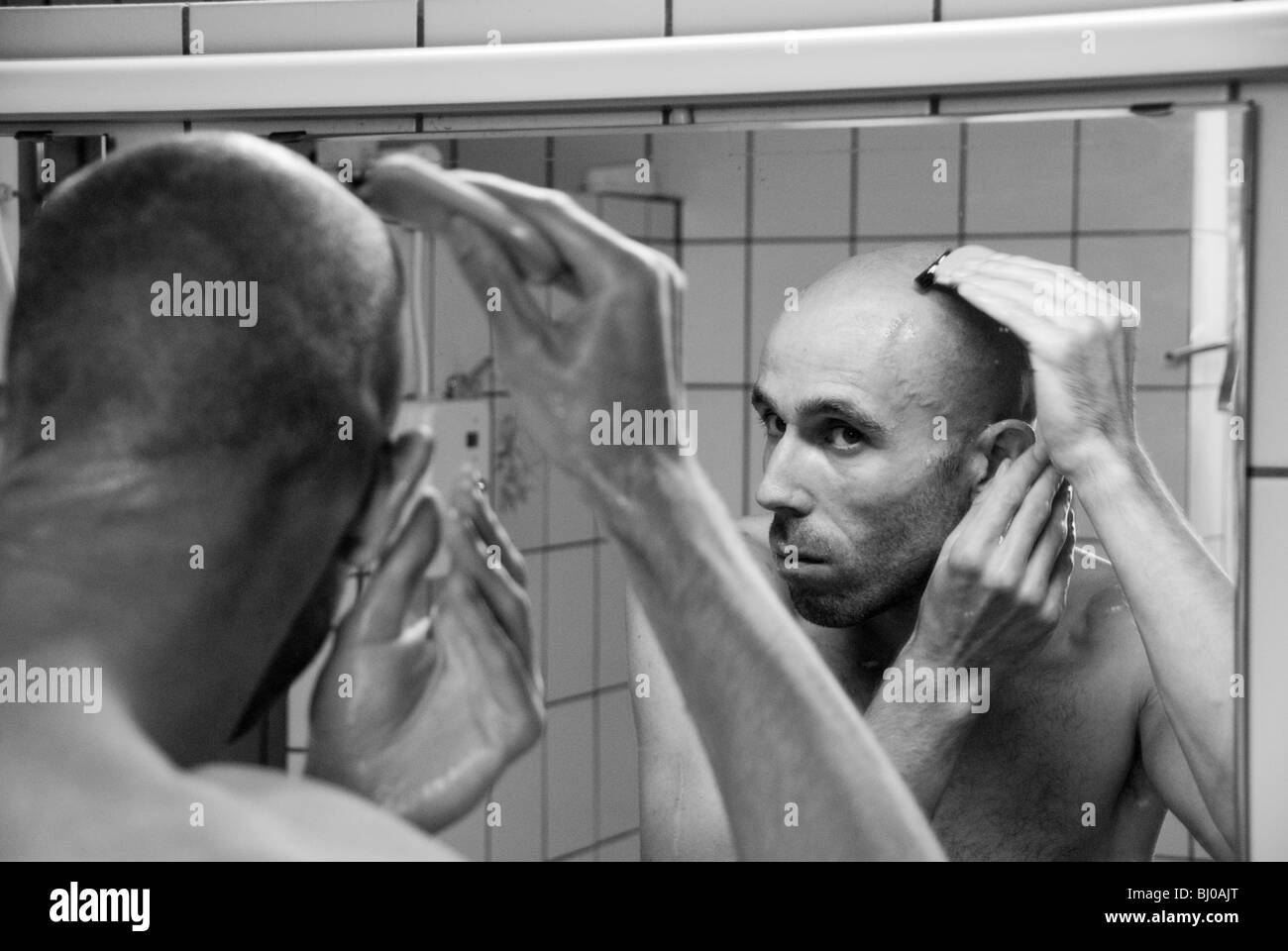 Un uomo rasa la testa in uno specchio in un campeggio Foto Stock